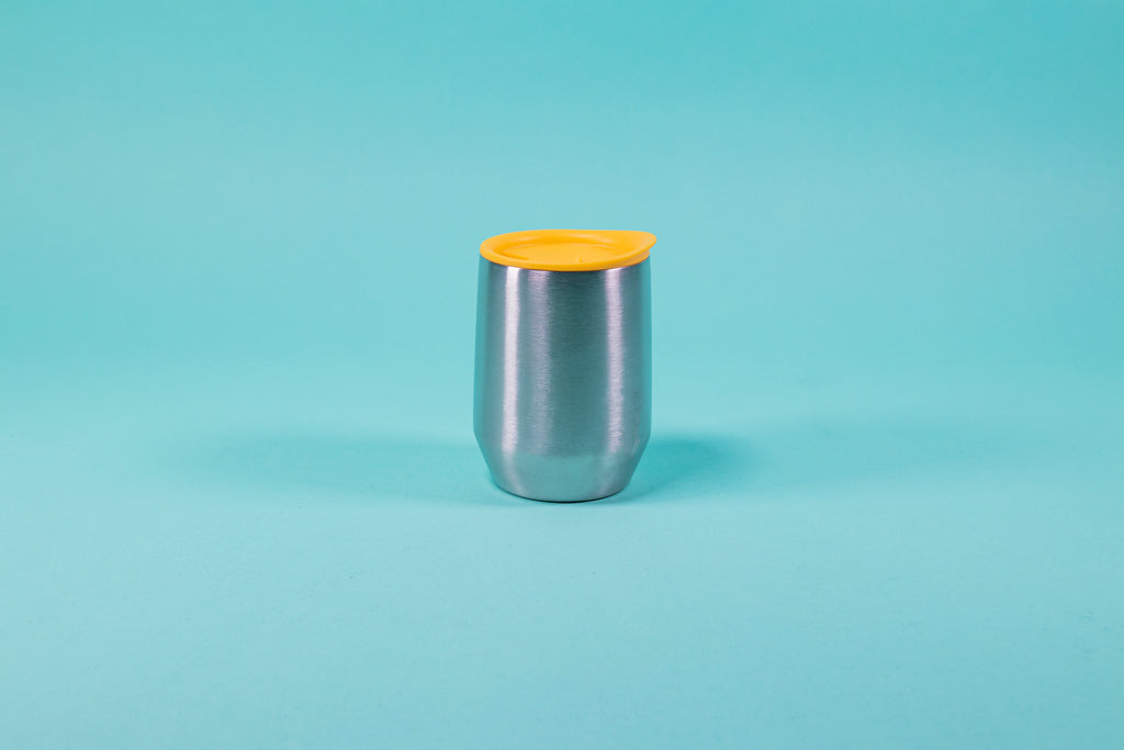 Short stainless steel insulated mug with yellow silicone lid set against a blue background.