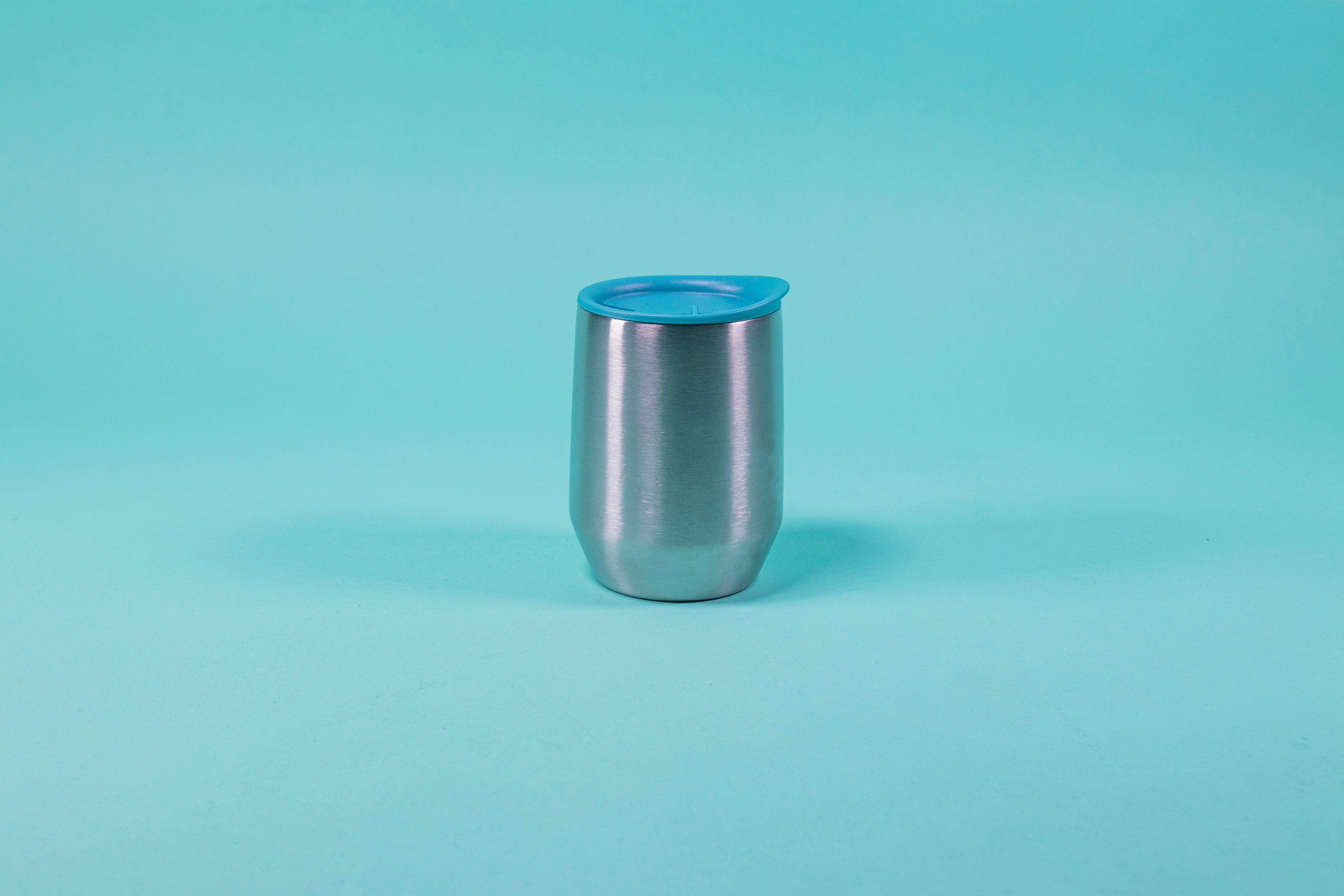 Short stainless steel insulated mug with light blue silicone lid set against a blue background.