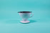 White ceramic cone shaped dripper with rounded edges and a black plastic filter insert on a blue background.