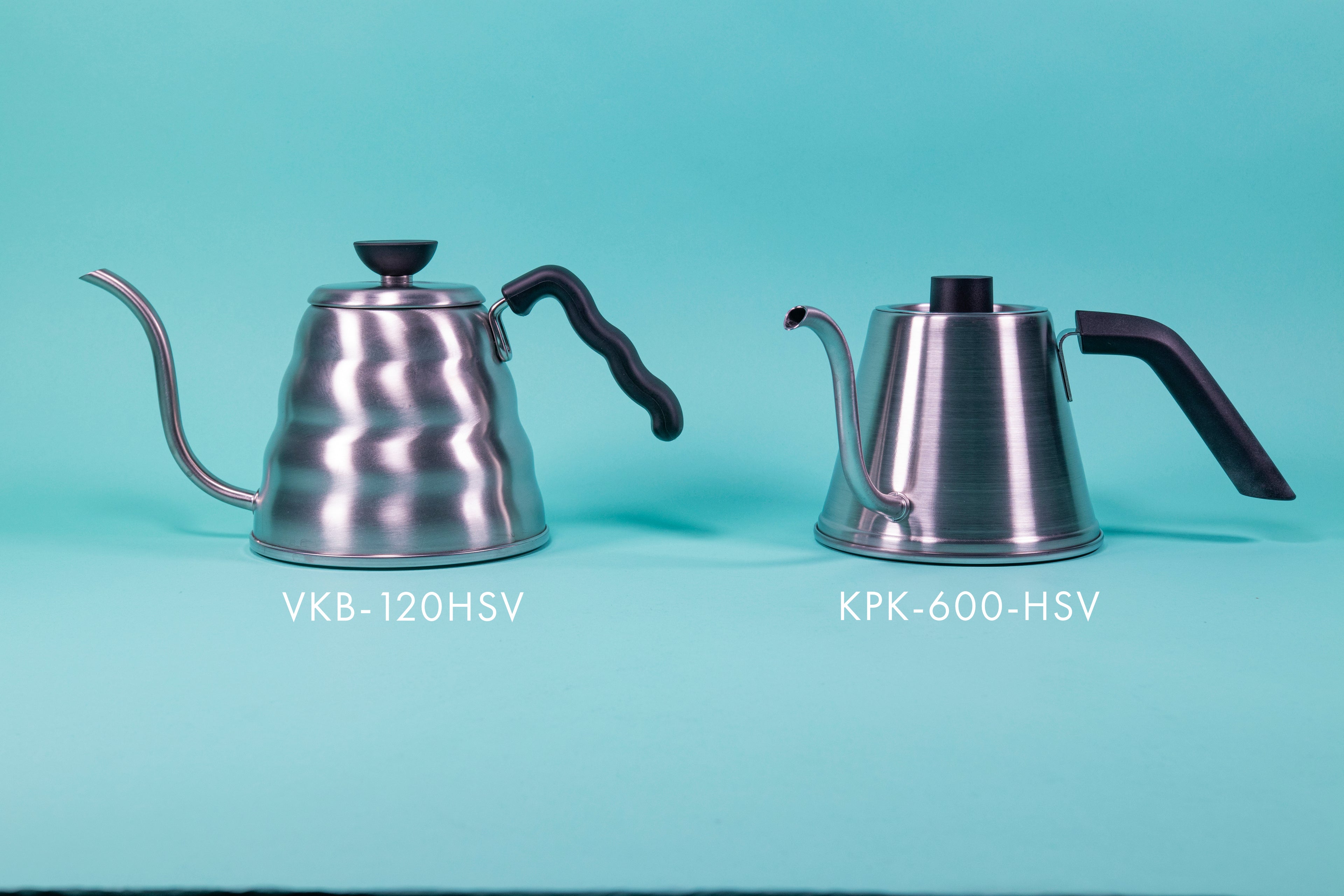 A beehive-shaped silver stainless steel handle with black plastic wave-shaped handle and black plastic lid knob with flat top beside a silver stainless steel kettle with black plastic handle and short cylindrical black plastic lid knob set against a blue background.