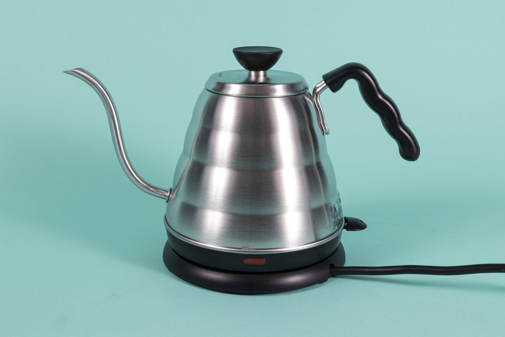 Stainless steel gooseneck kettle and matching lid with plastic base with red LED knob and black plastic covered handle on top a heating base with powercord on a teal backdrop.