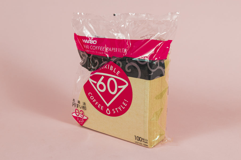 Large pack of brown cone filters in plastic packaging with round pink with white text "60" graphic on an orange backdrop.