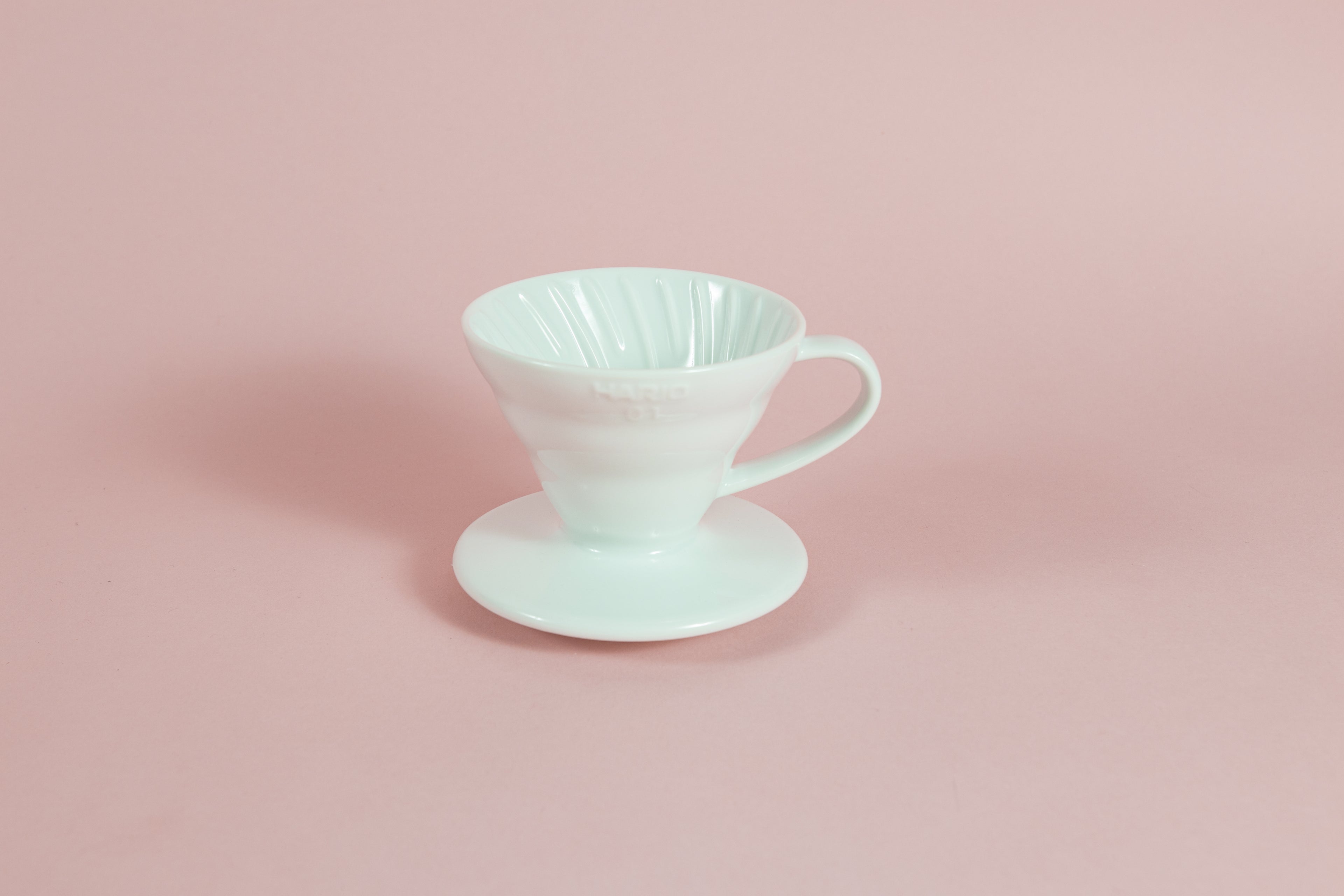 White cone shaped ceramic coffee dripper with handle and round base.