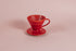 Red cone shaped ceramic coffee dripper with handle and round base.