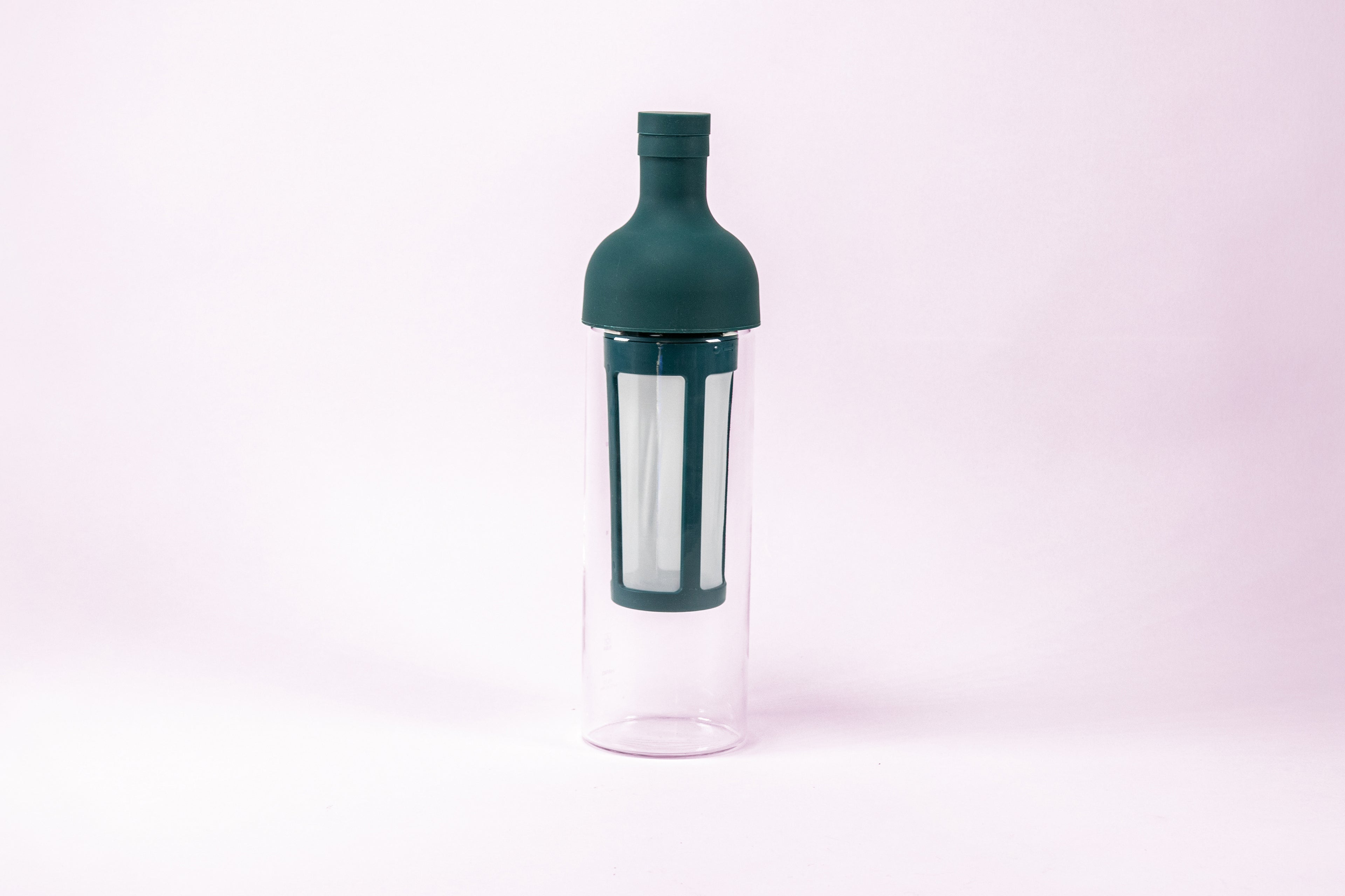 Tall glass container and white nylon mesh coffee filter, with teal rubber wine bottle shaped top.