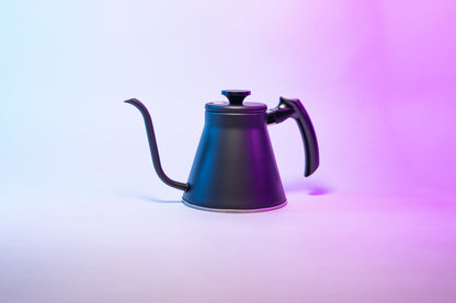 Matte black kettle with gooseneck spout, sloped black plastic handle and flat, black plastic lid knob set against a purple gradient background.