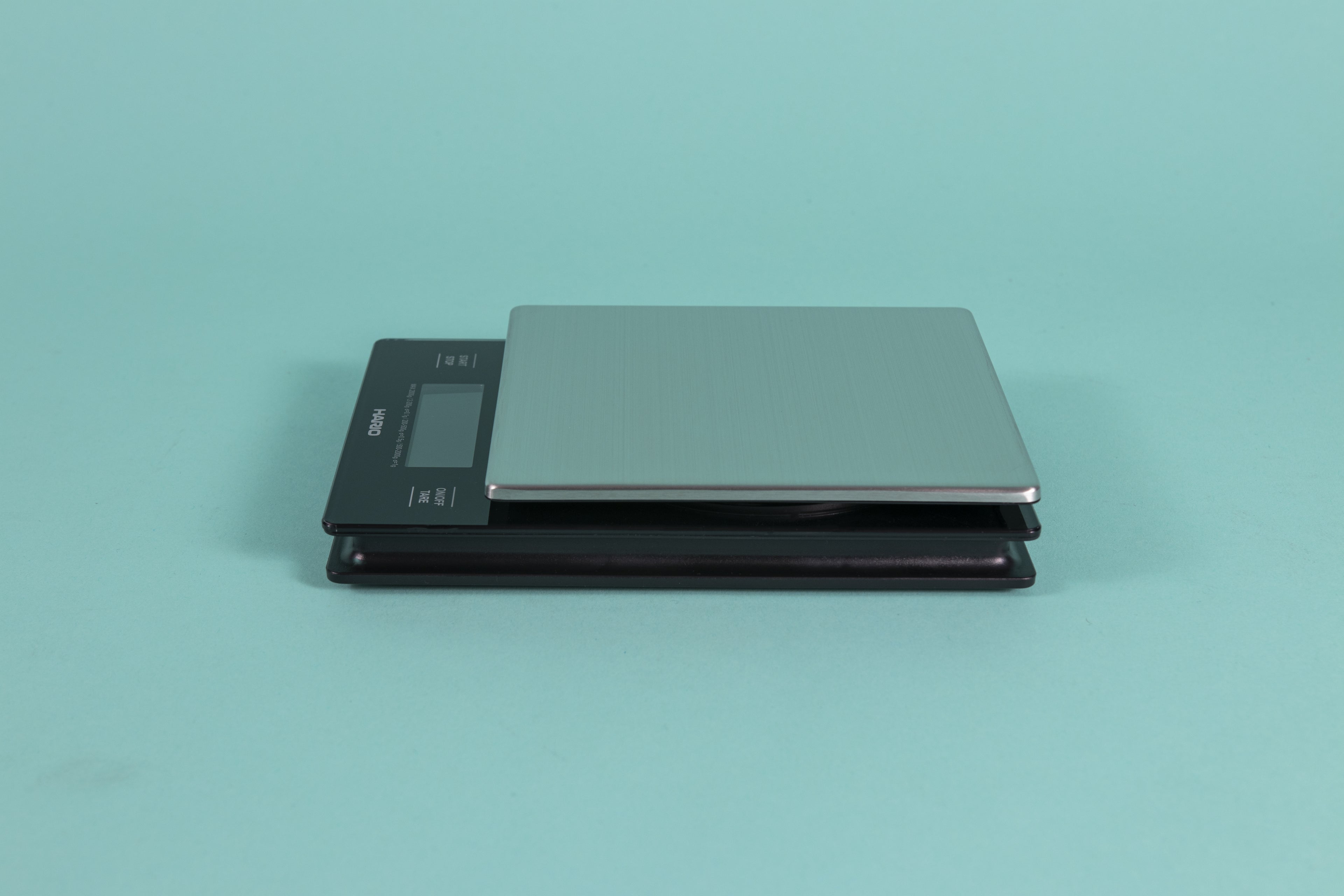 Black plastic scale with Digital LCD display and capacitive white text controls with a stainless steel weigh plate on a teal backdrop.