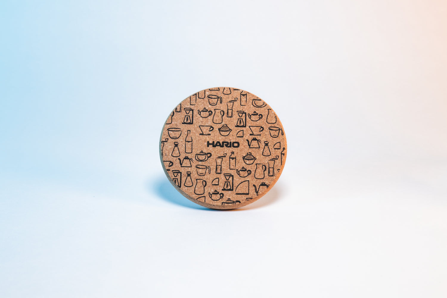 Circular cork coaster with black Hario logo and black pattern design of Hario products.