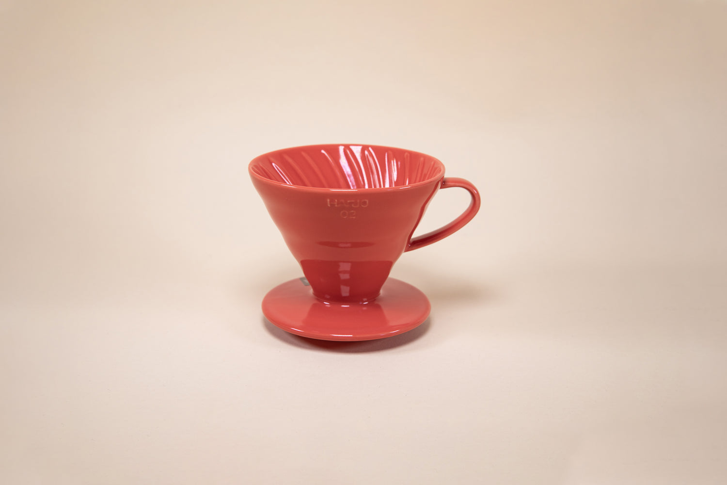 Red cone shaped ceramic coffee dripper with handle and round base.