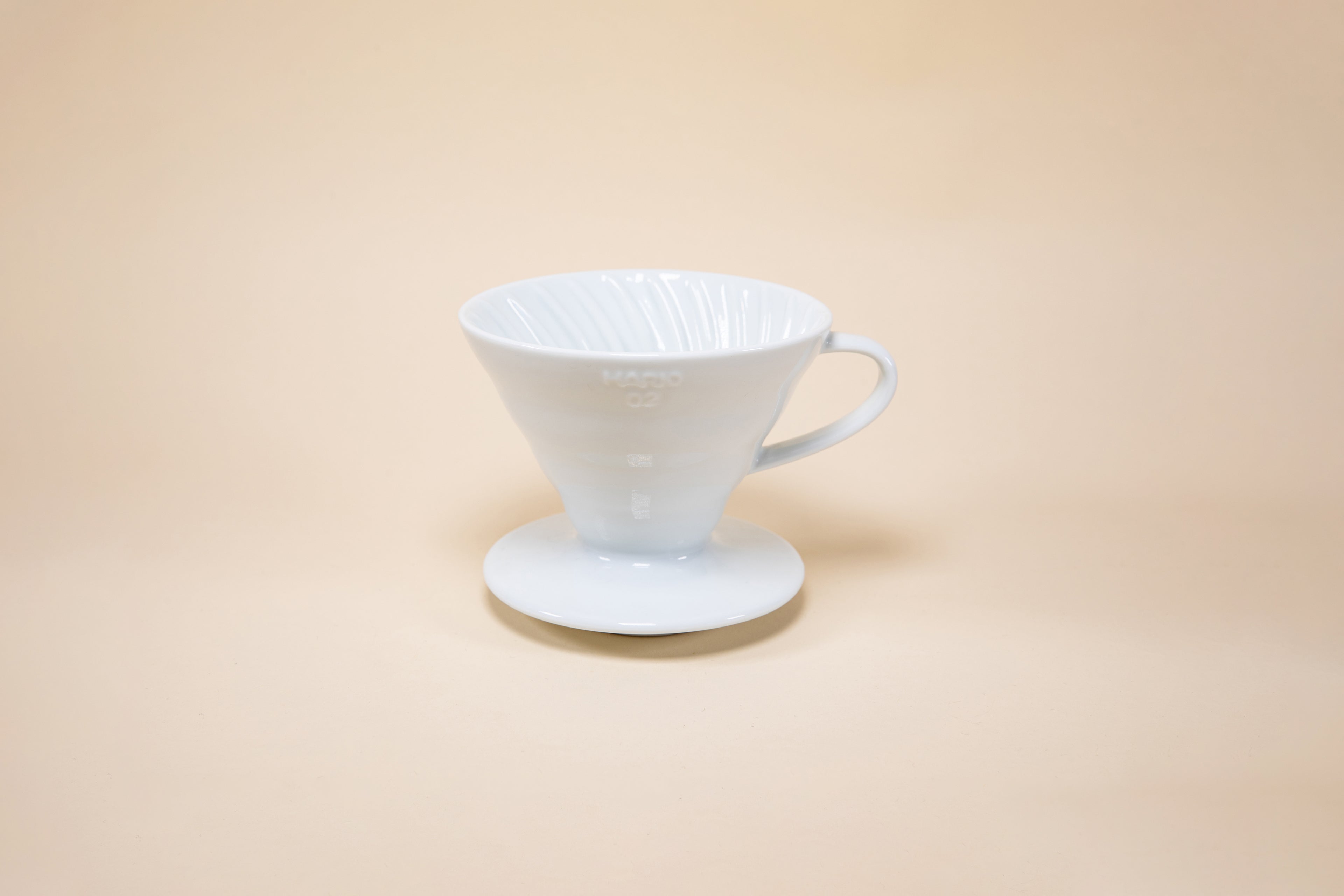 White cone shaped ceramic coffee dripper with handle and round base.
