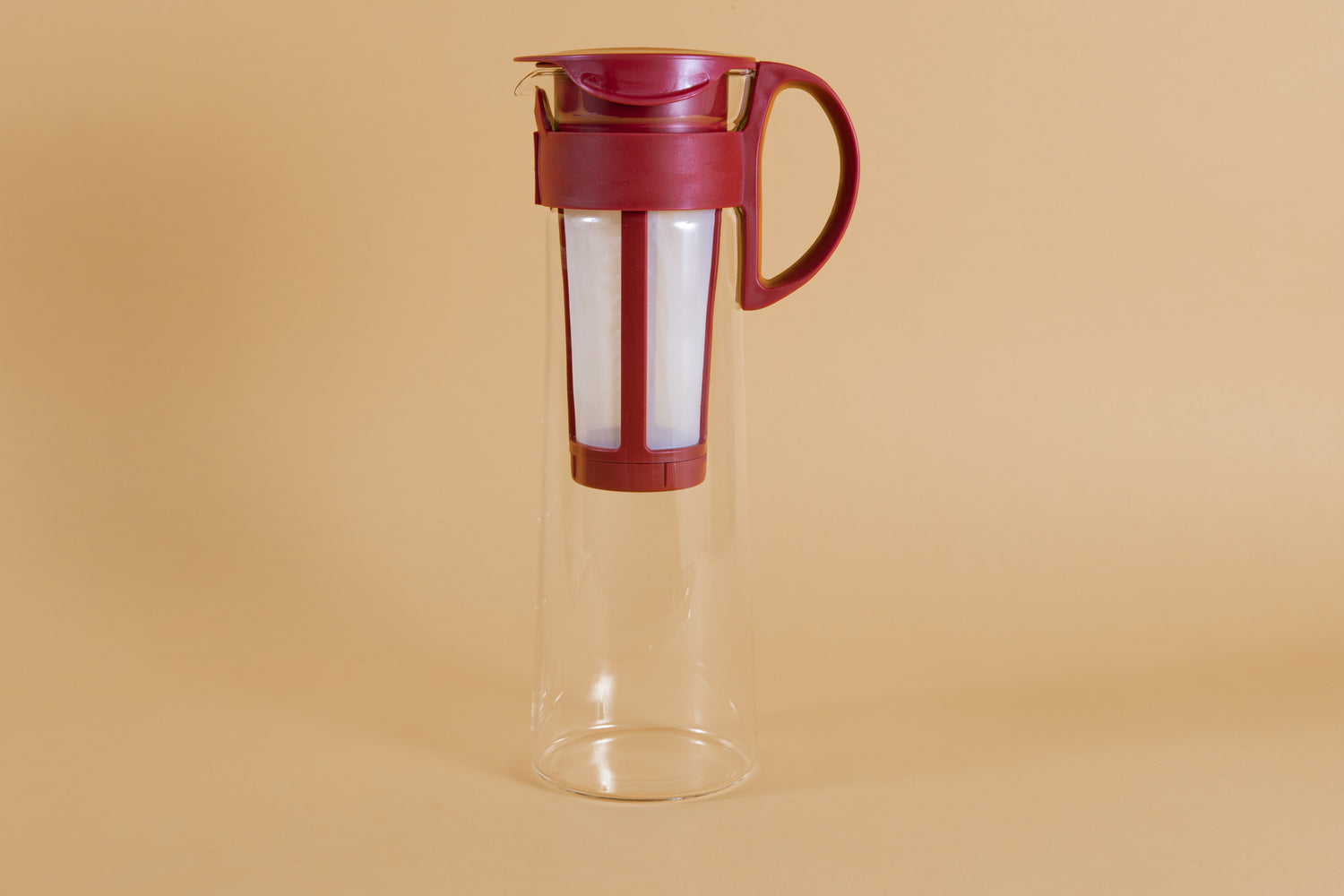 Tall glass server with white nylon mesh coffee filter insert and red plastic handle and lid.