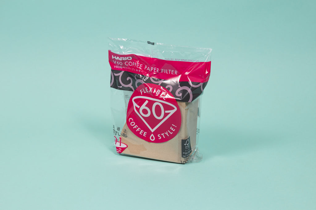 Brown cone shaped paper filters in a plastic bag with pink and black accents and set against a blue background.