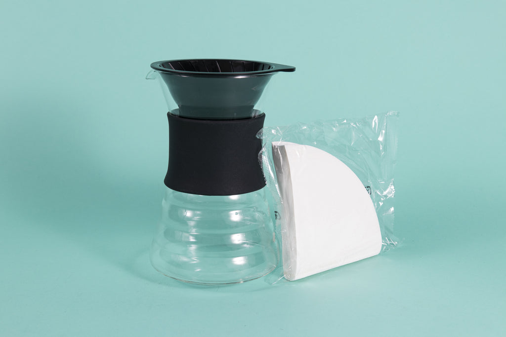 Tall glass decanter with rubber collar and plastic cone dripper insert with a pack of white cone filters.