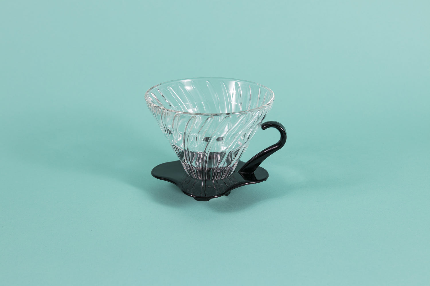 Clear all glass cone shaped coffee dripper with ribs, sitting in a black plastic base and handle.