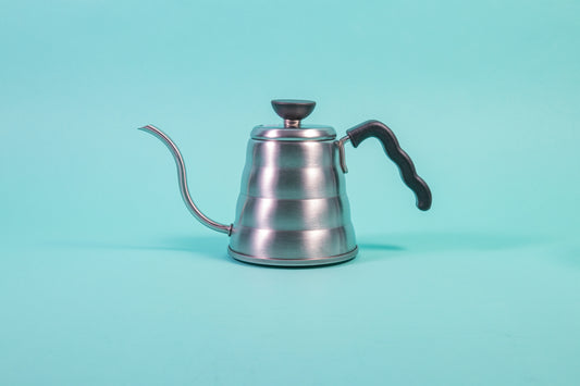 Silver beehive-shaped stainless steel kettle with wave-shaped black plastic handle and round black plastic lid knob with flat top set against a light blue background.