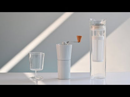 Link to YouTube video for the [Simply HARIO] Glass Cold Brew Coffee Pitcher | Glass Goblet | Ceramic Coffee Grinder. Person in video demonstrating milling with white grinder, the cold brew coffee maker and serving coffee in the glass goblet.